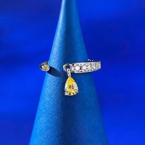 Macro detail of S925 silver ring with yellow pear-cut gemstone on a blue cone