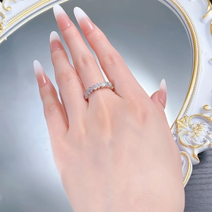 Macro detail of silver eternity band with rectangular and round diamonds worn on finger