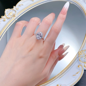 Close-up of 925 silver oval halo ring with sparkling stones worn on a woman finger