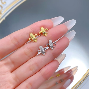 Macro detail of brushed matte iris stud earrings with micro-set zircons on hand