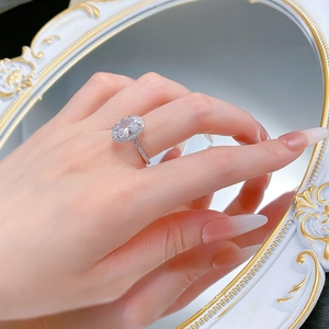 Macro shot of 925 silver halo ring with an oval center stone on a mirror background