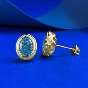 Macro view of S925 gold-plated stud earrings with 925 hallmark and blue ice-cut gem