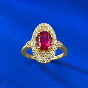 Detailed view of an oval red zircon ring with sparkling halo crystals and gold finish