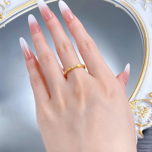 Close-up of golden ribbon ring with brushed texture and sparkling white crystals on hand