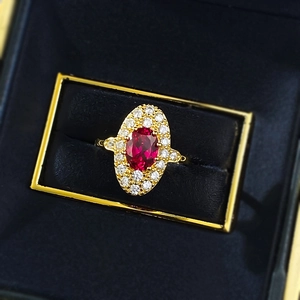 Macro shot of oval red zircon ring with double halo diamond setting in a black velvet box