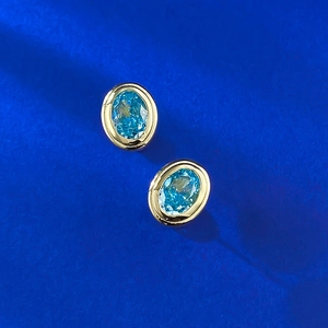 Close-up of S925 silver gold-plated stud earrings with blue ice-cut oval gemstones
