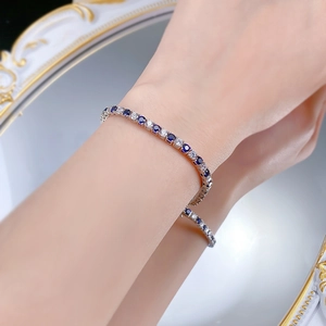 Gros plan d'un bracelet de tennis en argent S925 avec pierres bleues et blanches au poignet
