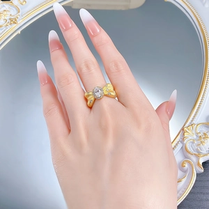Macro shot of S925 silver bow ring with brushed gold finish and oval crystal stone