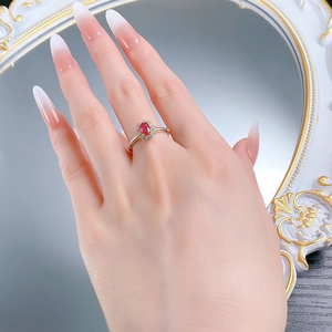 Macro shot of an oval red gemstone ring with diamond halo on a golden band