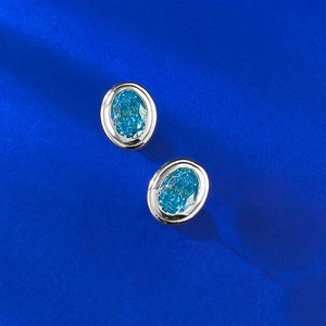 Close-up of S925 silver stud earrings with ice-cut blue aquamarine stones on dark background