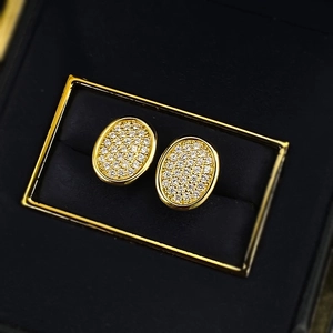 Macro detail of vintage gold oval stud earrings with pavé crystals in a jewelry box