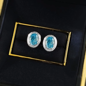 Macro detail of oval blue ice-cut crystal earrings in a premium black jewelry box