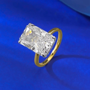Detailed view of rectangle radiant cut diamond ring with gold band on blue background