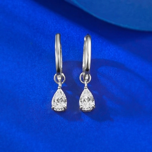 Détail de boucles d'oreilles en argent S925 avec pierres poire sur fond texturé bleu