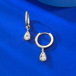 Gros plan de boucles d'oreilles argentées avec zircone en forme de goutte sur fond bleu