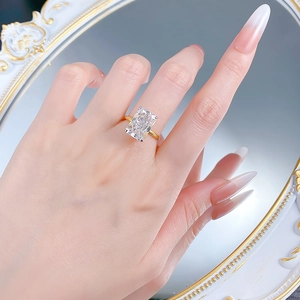 Close-up of rectangular ice-cut clear gemstone ring with golden four-prong setting