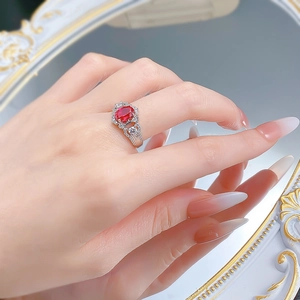 Detail of S925 silver ring with oval red gemstone and pavé halo on female finger