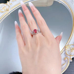 Detailed view of an S925 silver ring with a red oval gemstone and pavé settings on a finger