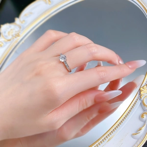Close-up of S925 silver four-prong round diamond ring on hand with vintage mirror background