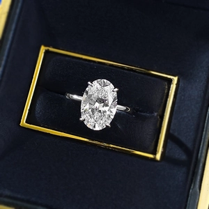 Macro view of oval cut solitaire diamond ring in four-prong setting inside velvet box