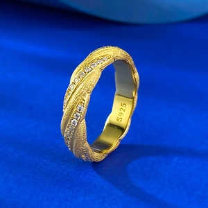 Macro shot of S925 silver ring with golden brushed texture and sparkling zircon inlay