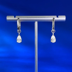 Gros plan de boucles d'oreilles poires avec pierres claires sur support argenté