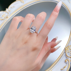 Detail of an oval-cut shimmering stone ring with classic four-prong silver setting on hand
