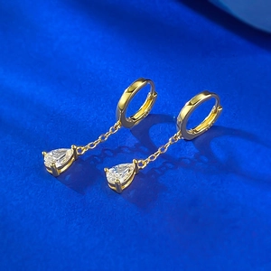 Detailed macro view of gold-plated tassel earrings featuring pear-cut cubic zirconia drop