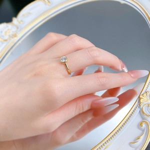 Gros plan d'une bague solitaire dorée de 6mm sertie clos portée par un mannequin au miroir