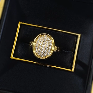 Macro detail of a gold-plated oval pavé ring with crystals in a black velvet jewelry box