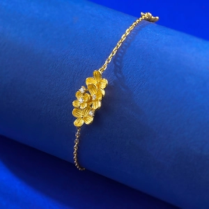 Elegant gold flower bracelet with silk texture petals and zircon accents on blue stand