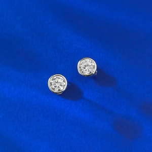 Close-up of S925 silver round bezel stud earrings with sparkling cubic zirconia on blue