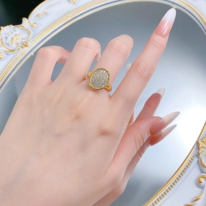 Detail of oval pavé cubic zirconia ring in gold finish worn on finger for an elegant look