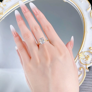 Detailed view of an emerald cut rectangular stone set in a gold band on a finger