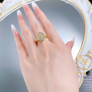 Close-up of gold-plated oval ring with pavé-set crystals worn on a finger
