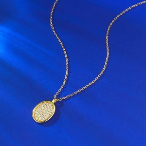 Makroaufnahme einer ovalen Goldkette mit Kristallbesatz auf blauem Samthintergrund