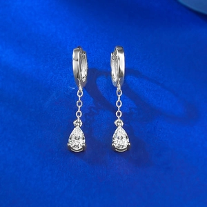 Macro detail of S925 silver huggie earrings featuring delicate pear-cut zircon tassels