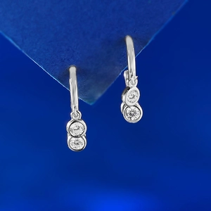 Detail of silver drop earrings with dual circular clear crystals on blue background