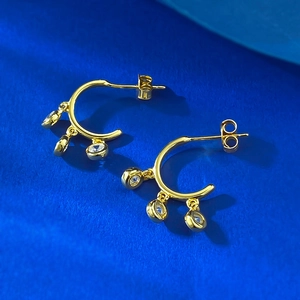 Detail of gold-plated C-shaped earrings with three hanging clear cubic zirconia crystals