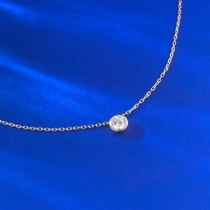 Vue macro d'un collier en argent S925 avec zircon blanc rond sur un fond en soie bleue