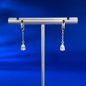 Detailed view of silver drop earrings with pear-cut zircon and tassel chains on a stand