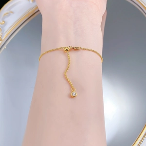 Detail of adjustable gold S925 silver bracelet with a single sparkling crystal charm
