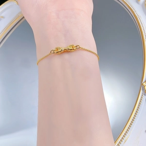 Close-up of a gold Vajra charm bracelet with diamonds on a woman's wrist