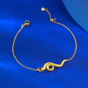 Macro detail of golden S925 silver snake bracelet with ruby eye on blue background