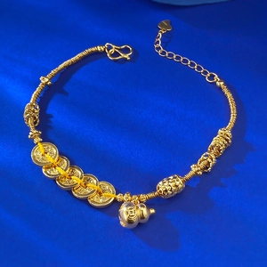 Gros plan d'un bracelet doré avec gourde hulu et cinq pièces sur soie bleue