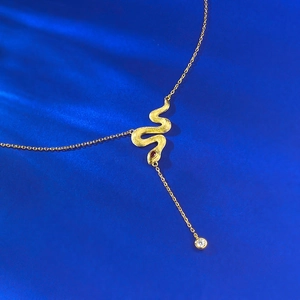 Detailed macro view of gold snake pendant with brushed texture and red gemstone eye