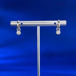 Macro shot of silver plated drop earrings with round cubic zirconia on a jewelry stand