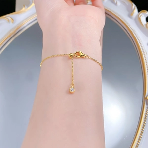 Detail of gold snake chain bracelet featuring a lobster clasp and sparkling zircon charm