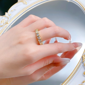Detail of eternity ring with square cut crystals on gold band reflected in a mirror
