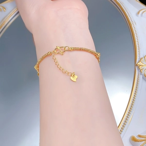 Détail d'un bracelet en or 999 avec design en fil enveloppé et pendentif en cœur